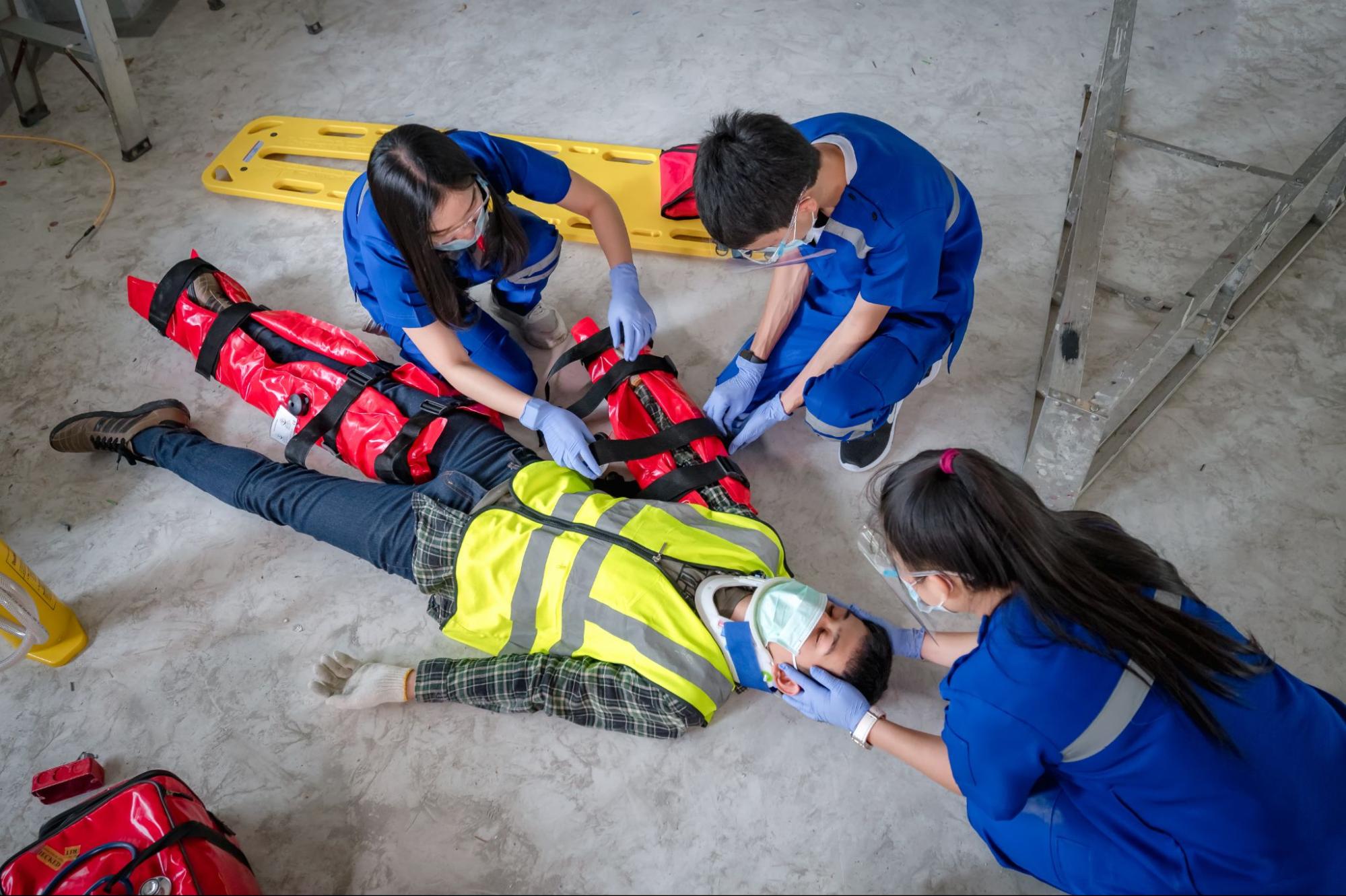 Emergency responders providing first aid to an injured construction worker on site