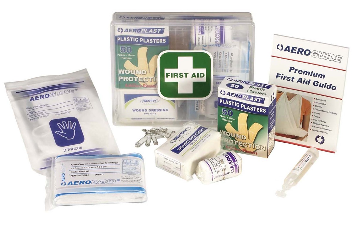 Contents of an Aero Essentials first aid kit displayed on a white background, including a hard plastic first aid case, adhesive plasters, wound dressings, bandage, gloves, saline ampoule, safety pins and a first aid guide.